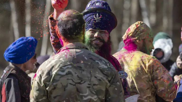 A Sikh in traditional attire is pictured sprinkling neon powder on a British Army soldier.