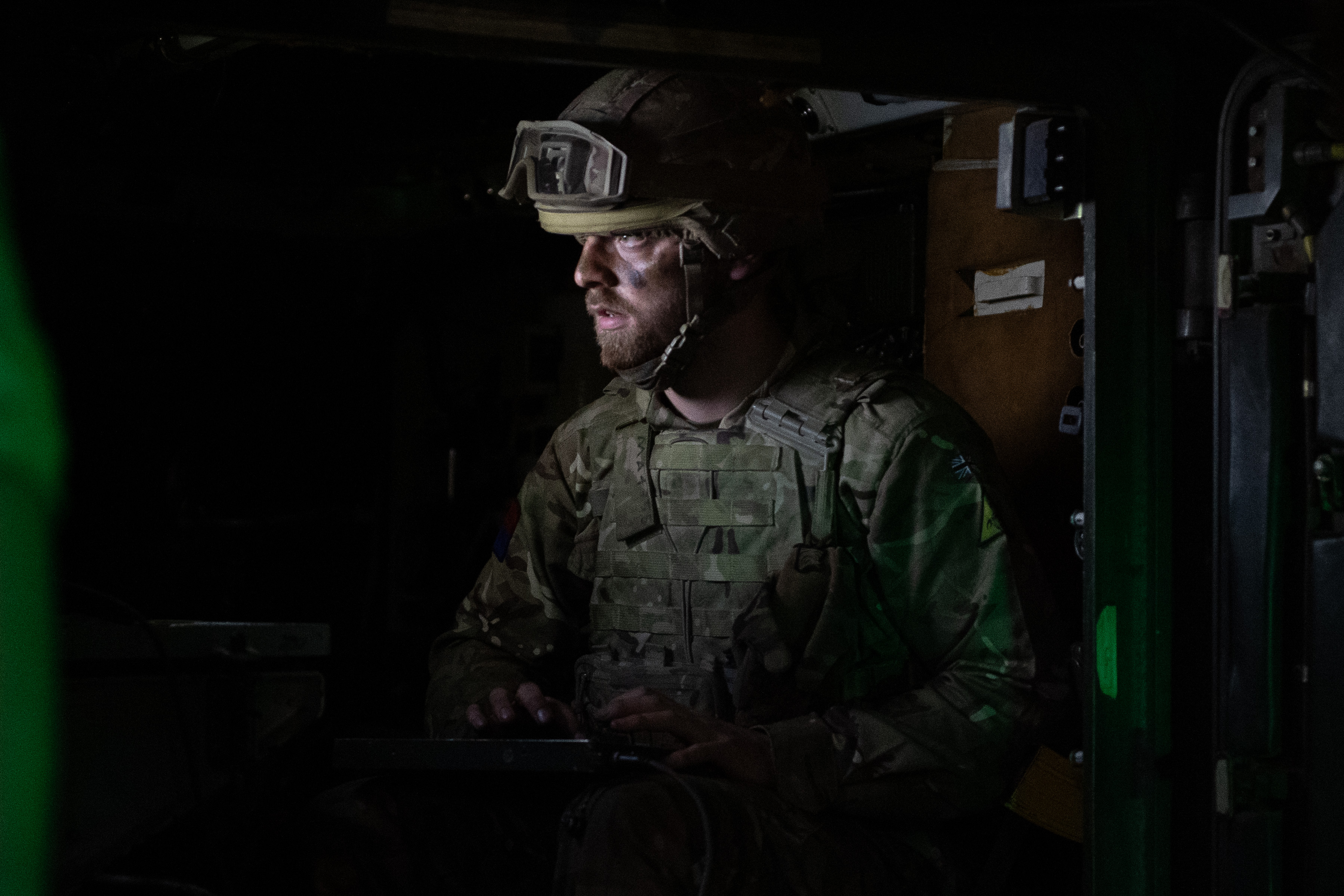 A soldier stands in a darkened room.