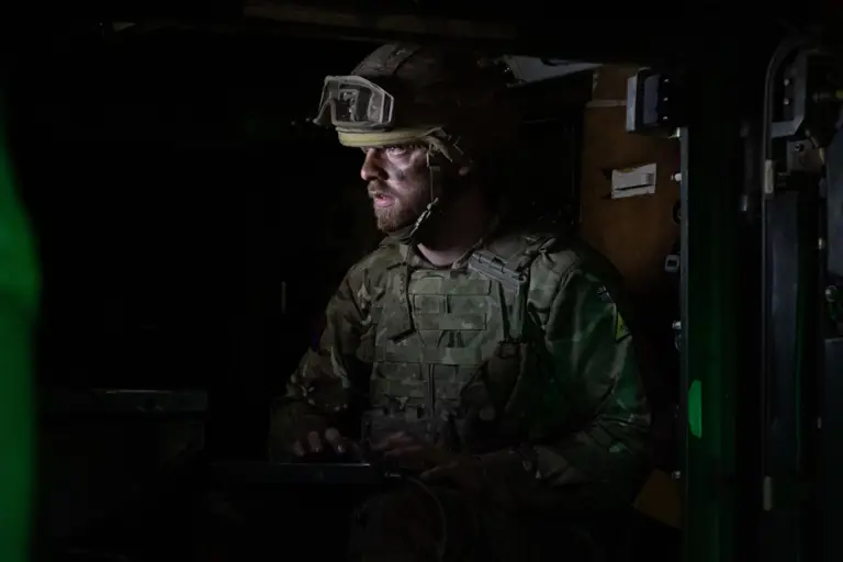 A soldier stands in a darkened room.