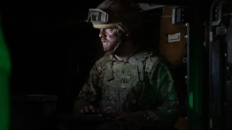 A soldier stands in a darkened room.
