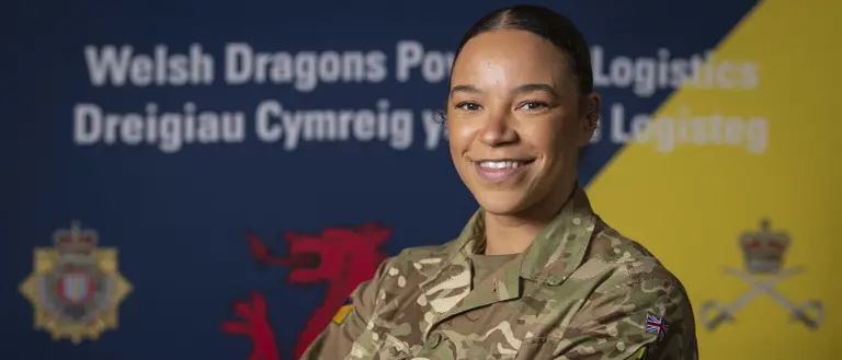 British Army soldier in camouflage uniform stands confidently with arms crossed against a backdrop featuring Welsh and logistics symbols.