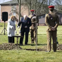 Holocaust survivors Mala Tribich MBE and Dr Alfred Garwood MBE light Holocaust candles on an army camp during a memorial service. Surrounded by several soldiers in their number 2 uniforms.