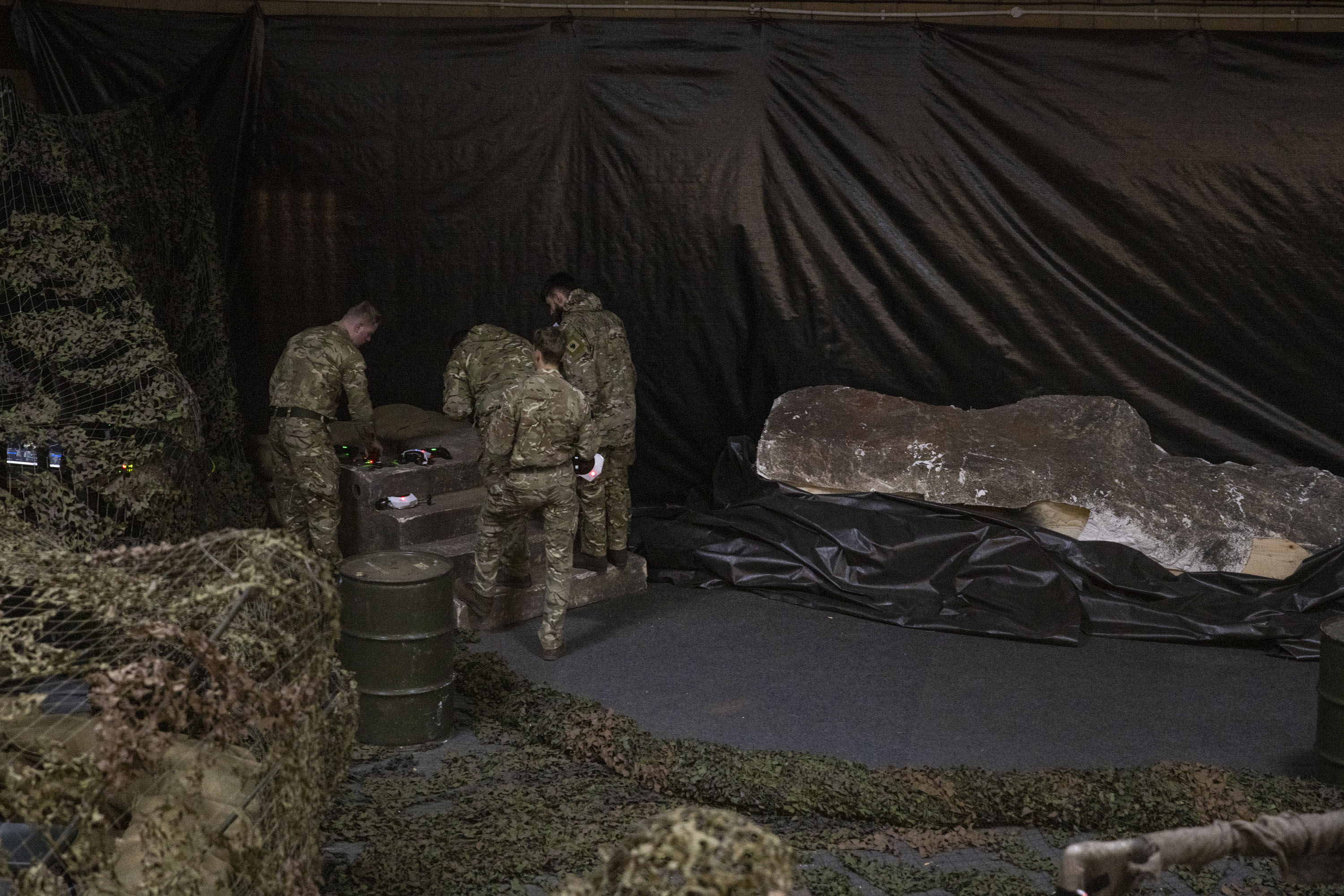 Four men in uniform are pictured setting up drones.