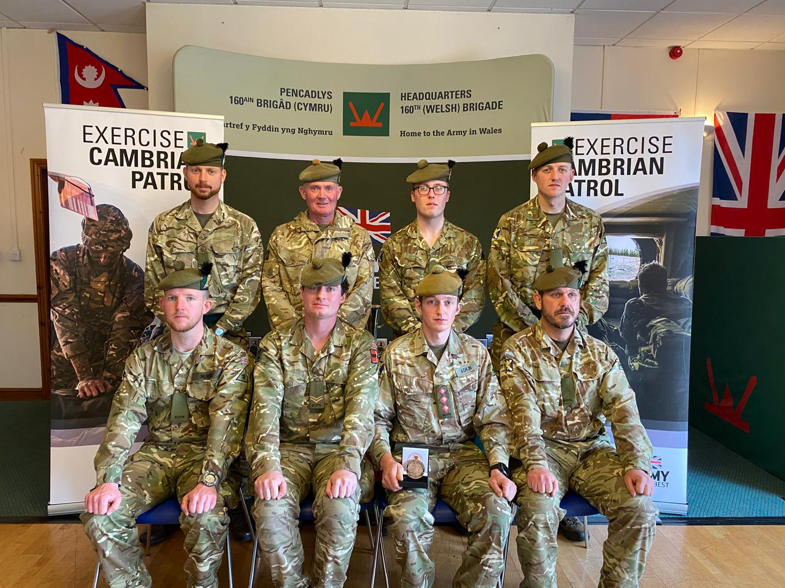 Several men in uniform are pictured with a Cambrian Patrol medal.