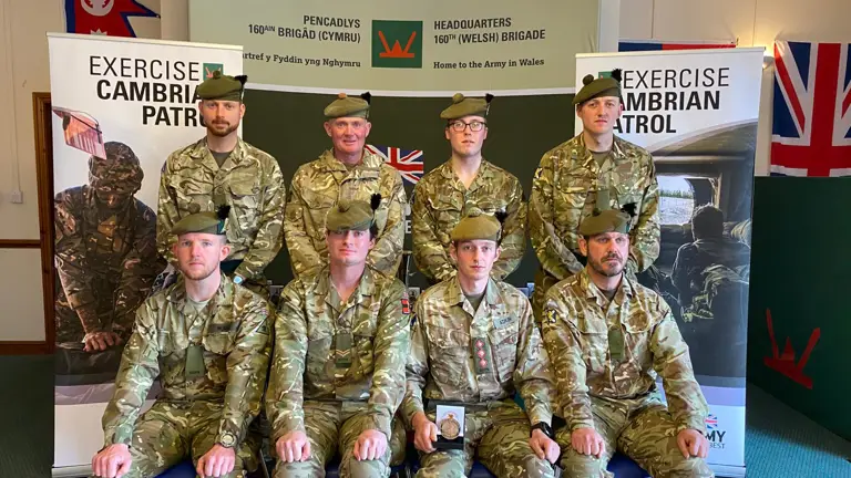 Several men in uniform are pictured with a Cambrian Patrol medal.