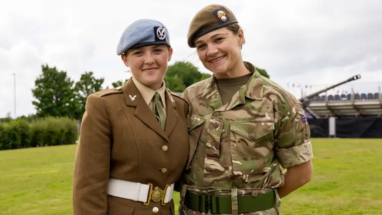 Chloe is photographed in her brown uniform and blue Army Air Corps beret stood next to her mum Sherene who is dressed in her camouflage uniform. They are both smiling and have their arms around each others back.