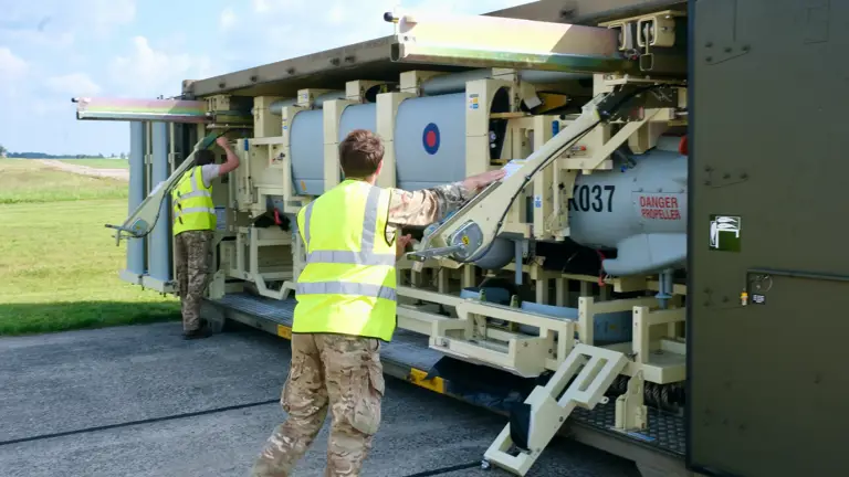An unmanned aerial vehicle is pictured being unloaded by two men in uniform and high-vis jackets.