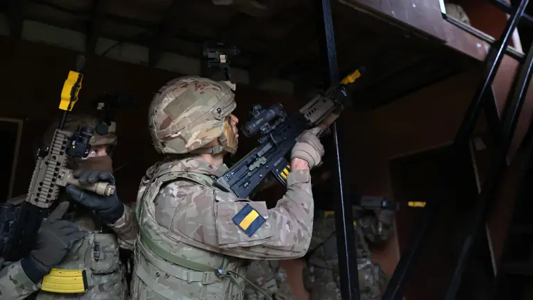 Soldiers wearing camouflage uniforms hold their rifles during a building clearance.