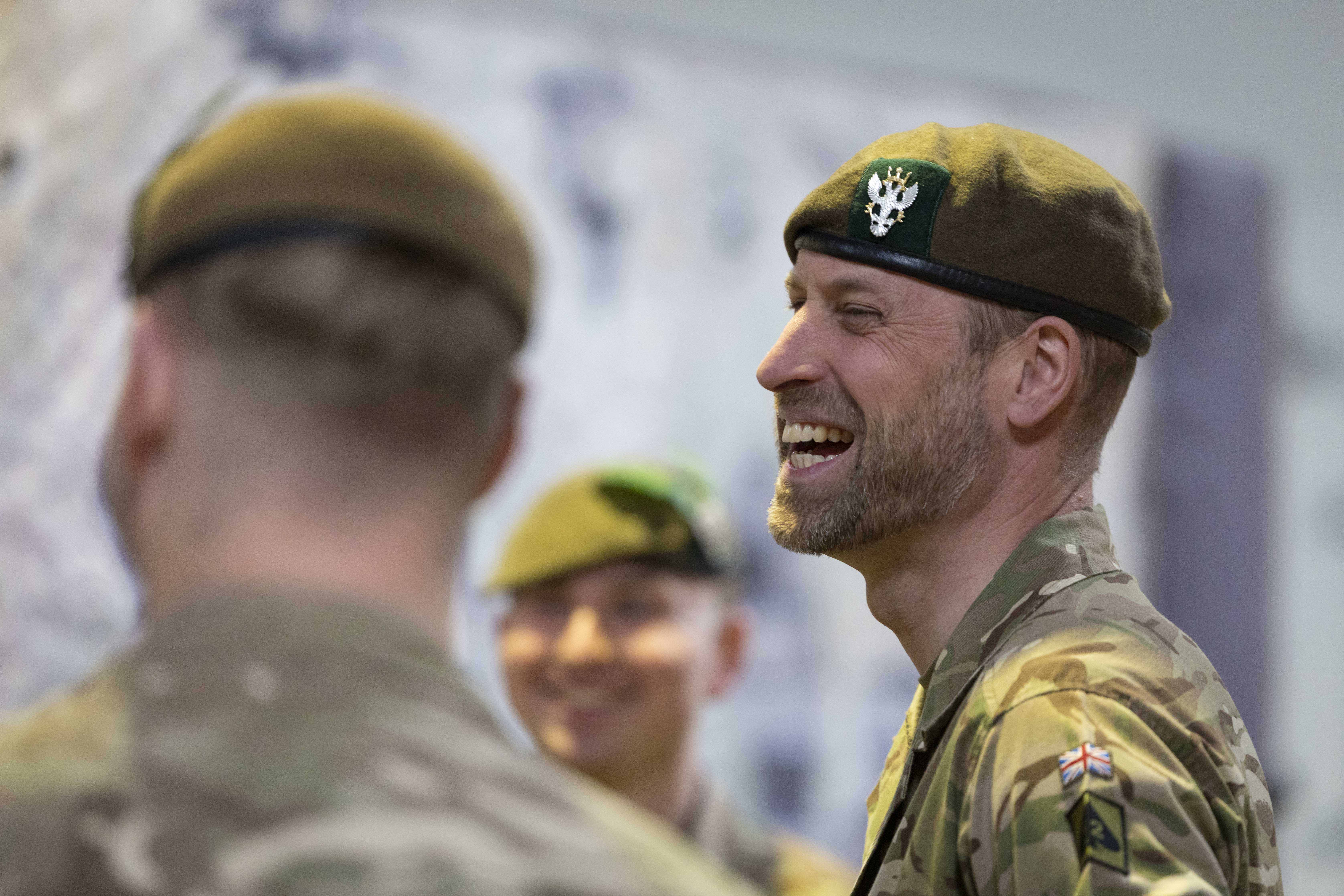 Three individuals in military uniforms are standing together, smiling. 