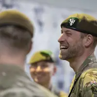 Three individuals in military uniforms are standing together, smiling.