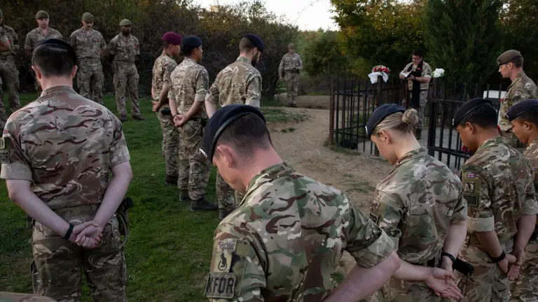 Soldiers bow their heads in a ceremony of remembrance.