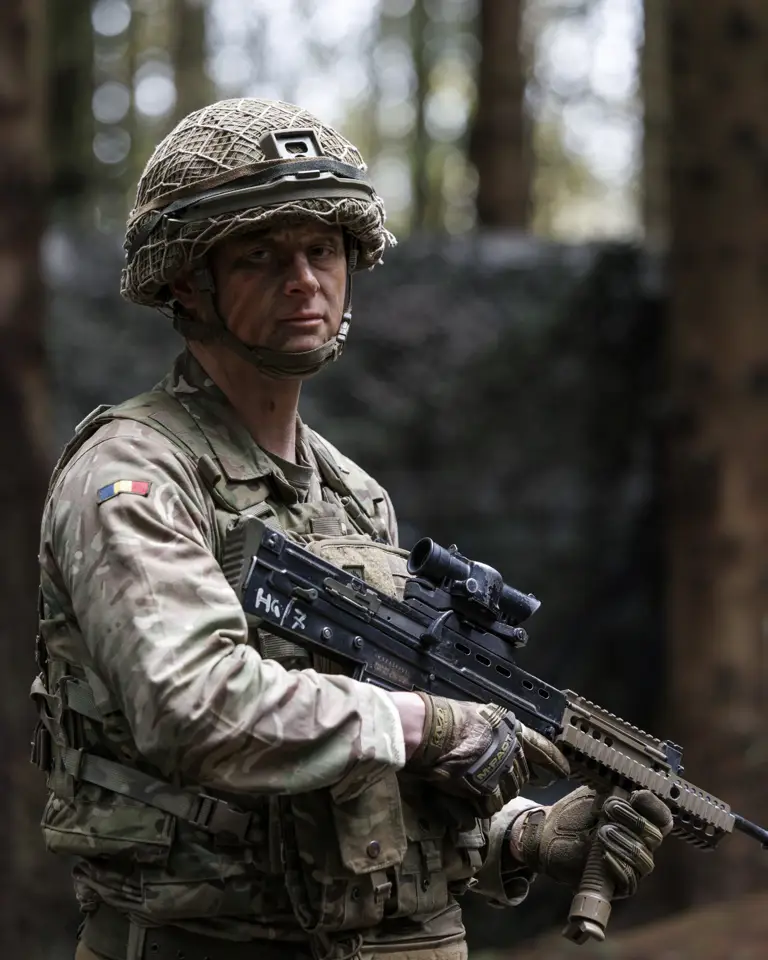 Soldier in camouflage gear holding a rifle in a forest setting during training.