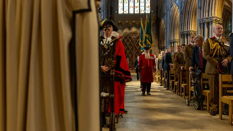 Inside the cathedral soldiers and guests line the chairs each side of the aisle. The colours are being marched down the aisle in uniform.
