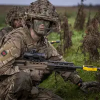 A soldier wearing camouflage uniform takes a knee during a training serial.