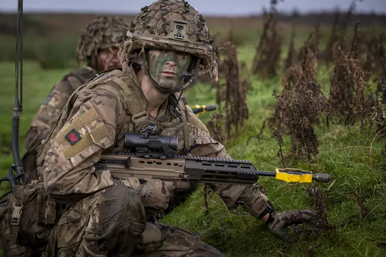 A soldier wearing camouflage uniform takes a knee during a training serial.