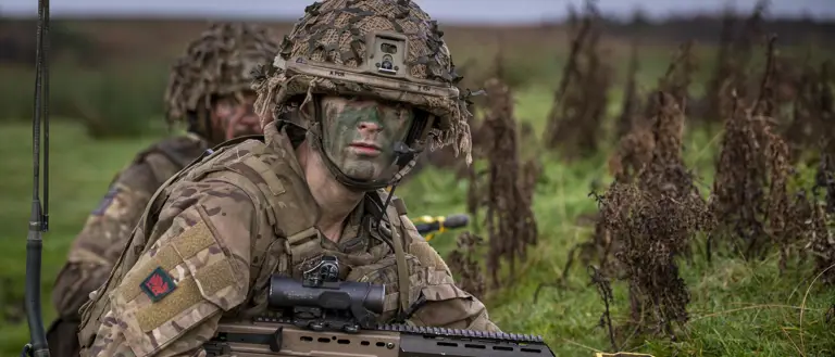 A soldier wearing camouflage uniform takes a knee during a training serial.