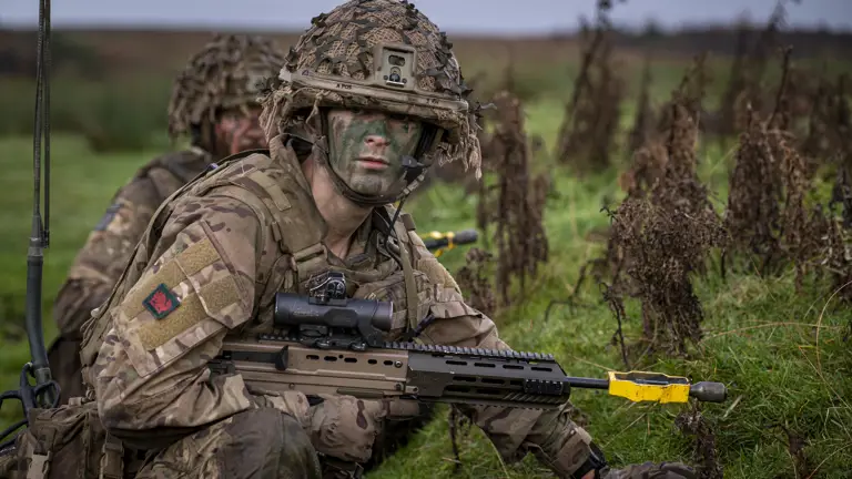 A soldier wearing camouflage uniform takes a knee during a training serial.