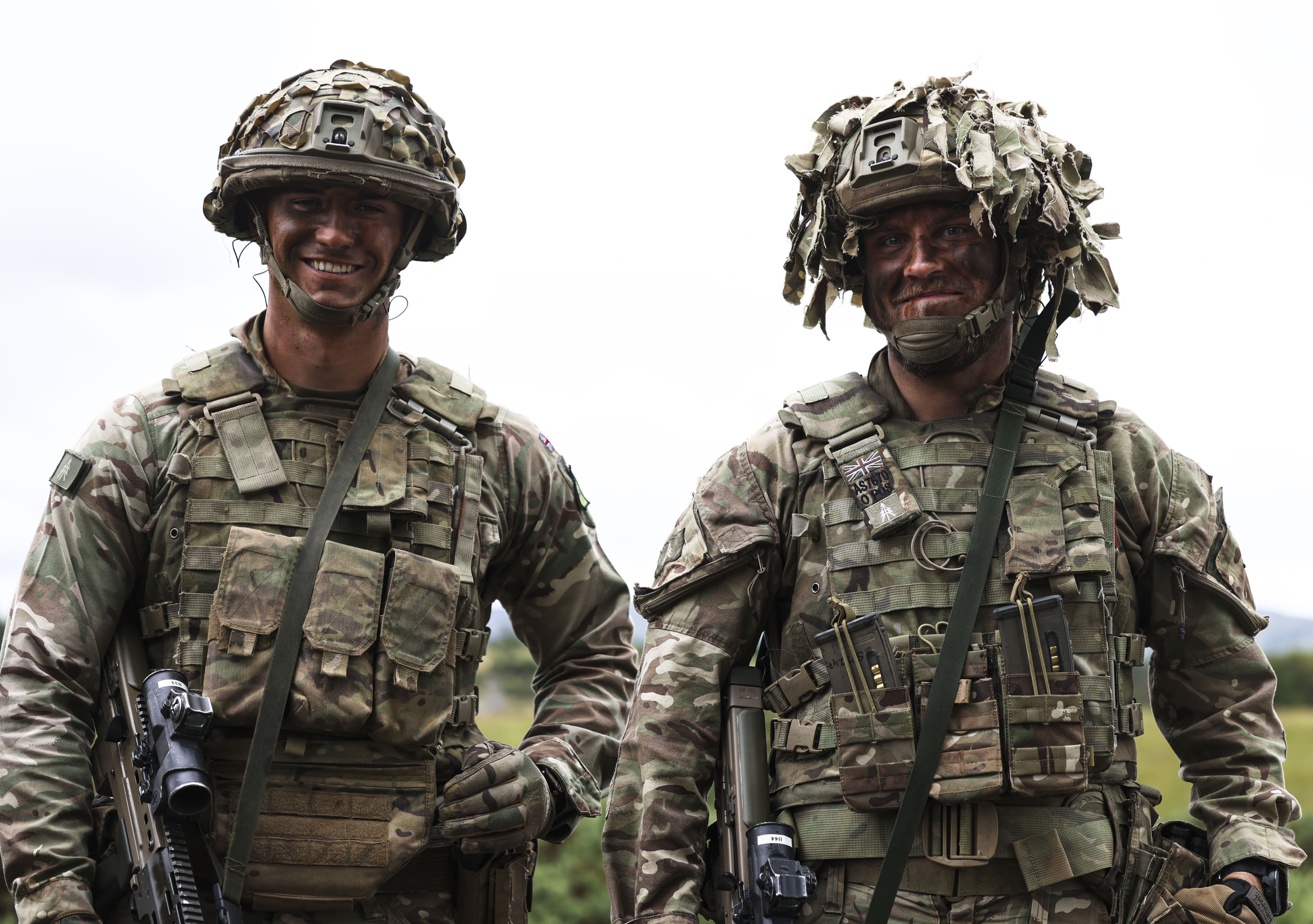 Group of soldiers in camouflage uniforms communicating outdoors during a training exercise.