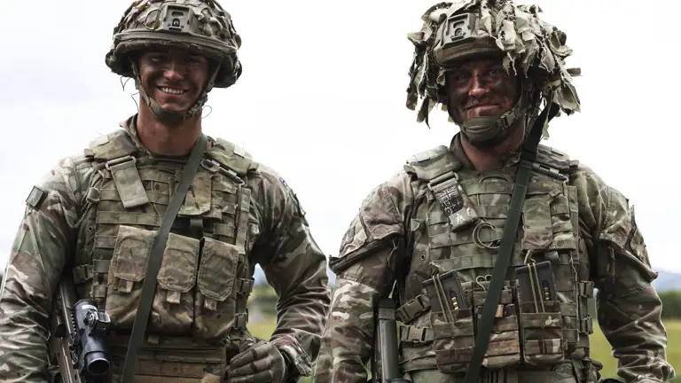 Group of soldiers in camouflage uniforms communicating outdoors during a training exercise.