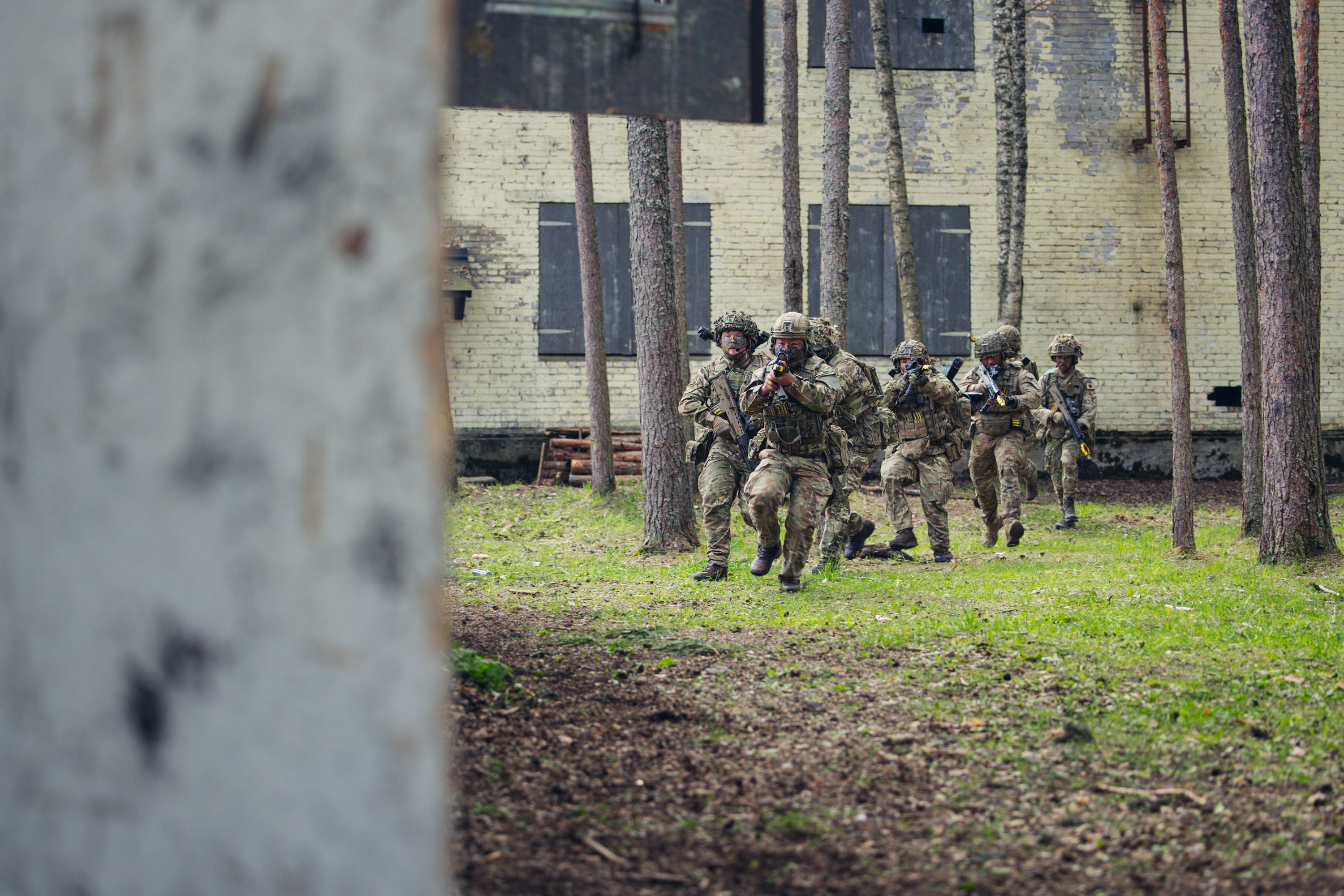 Several soldiers are pictured with their weapons outside of a building.