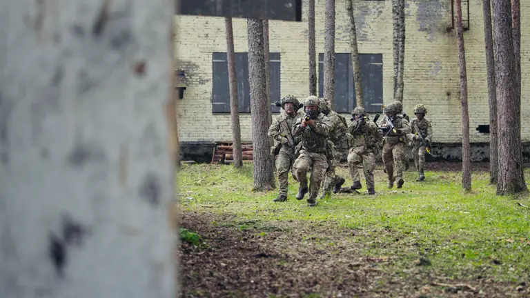 Several soldiers are pictured with their weapons outside of a building.