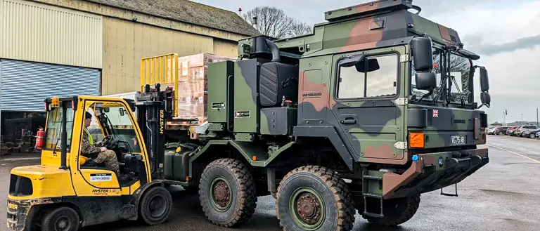 A forklift loads supplies onto a military enhanced pallet loading system.