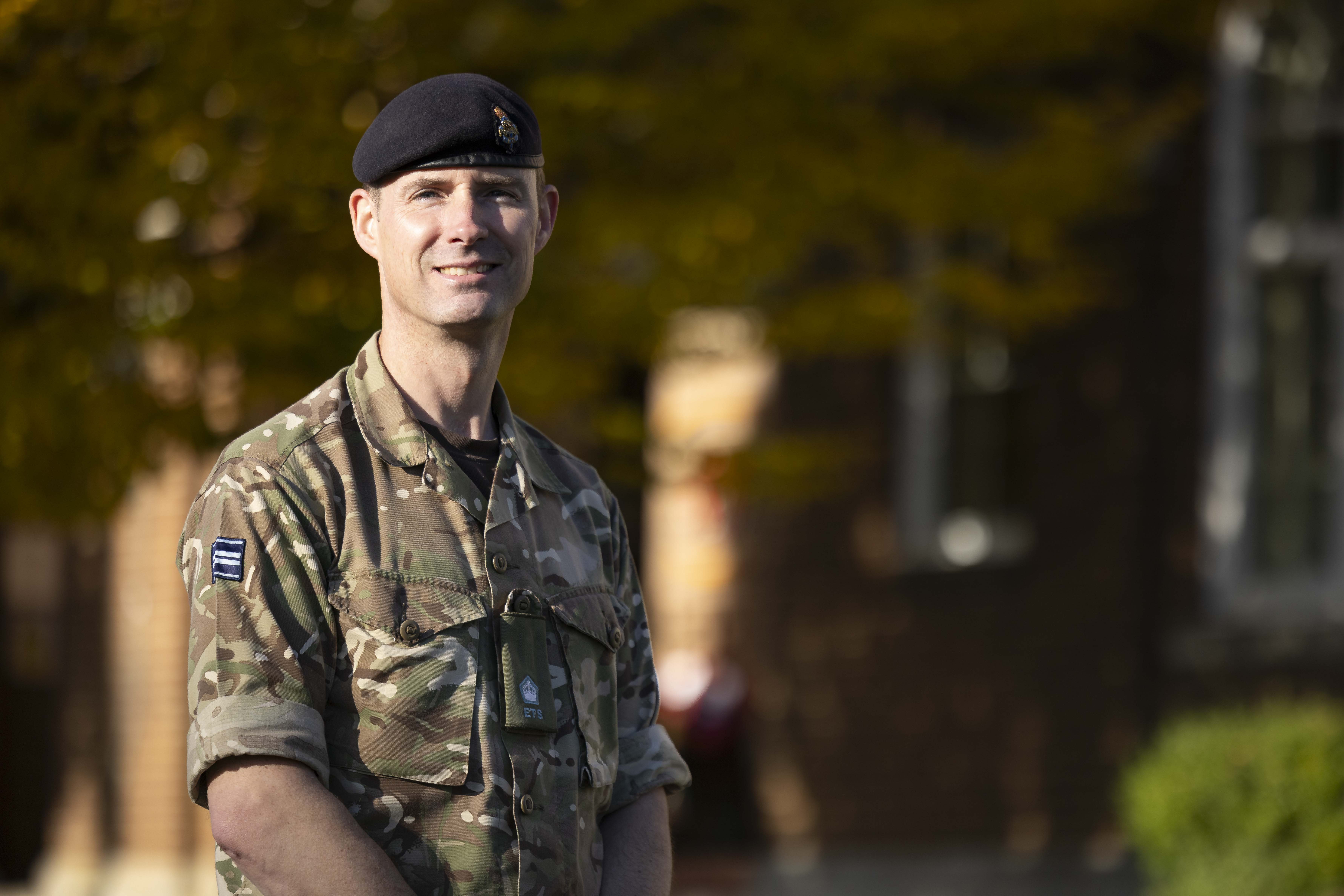 A soldier stands for a portrait in front of a building.