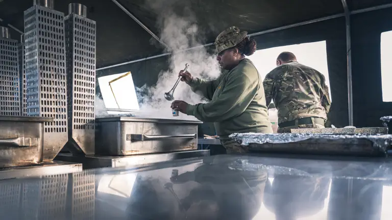 Two Royal Logistic Corps Chefs wearing camouflage uniform seen prepping in a field kitchen to feeding the troops.