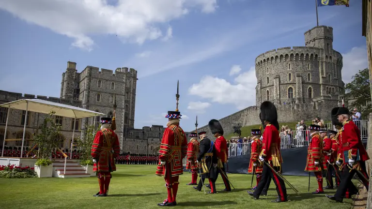 His Majesty The King is escorted by soldiers wearing red tunics and bearskin hats.