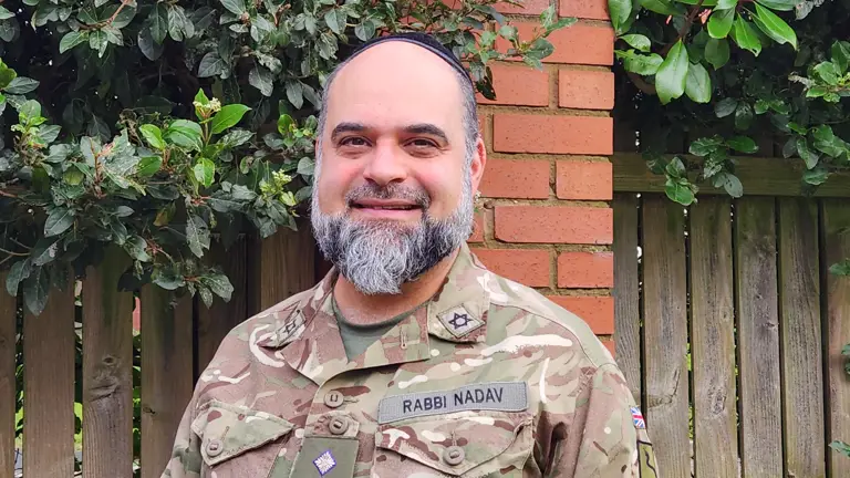 Rabbi Nir Nadav shown smiling for a portrait wearing his uniform and jewish headdress.