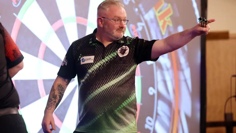Darts player in a black and green shirt.