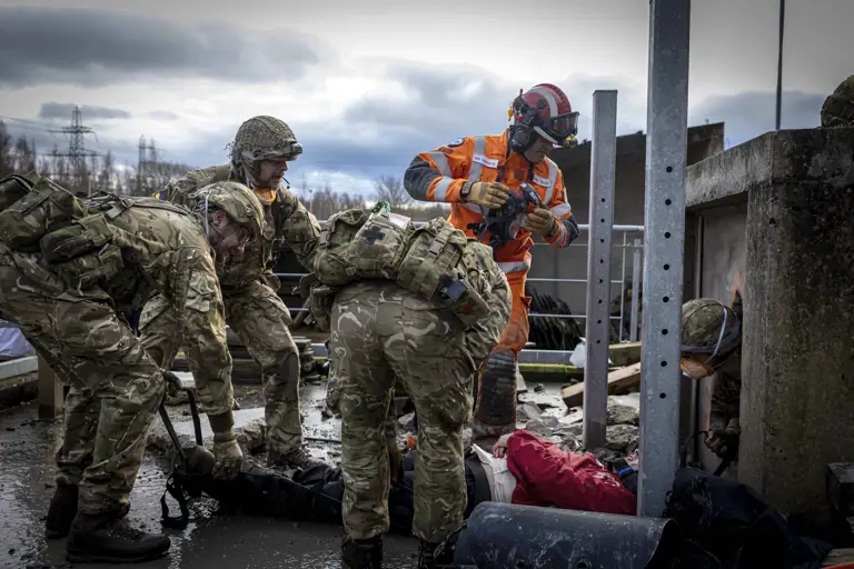 Soldiers in camouflage uniforms assist injured individuals.