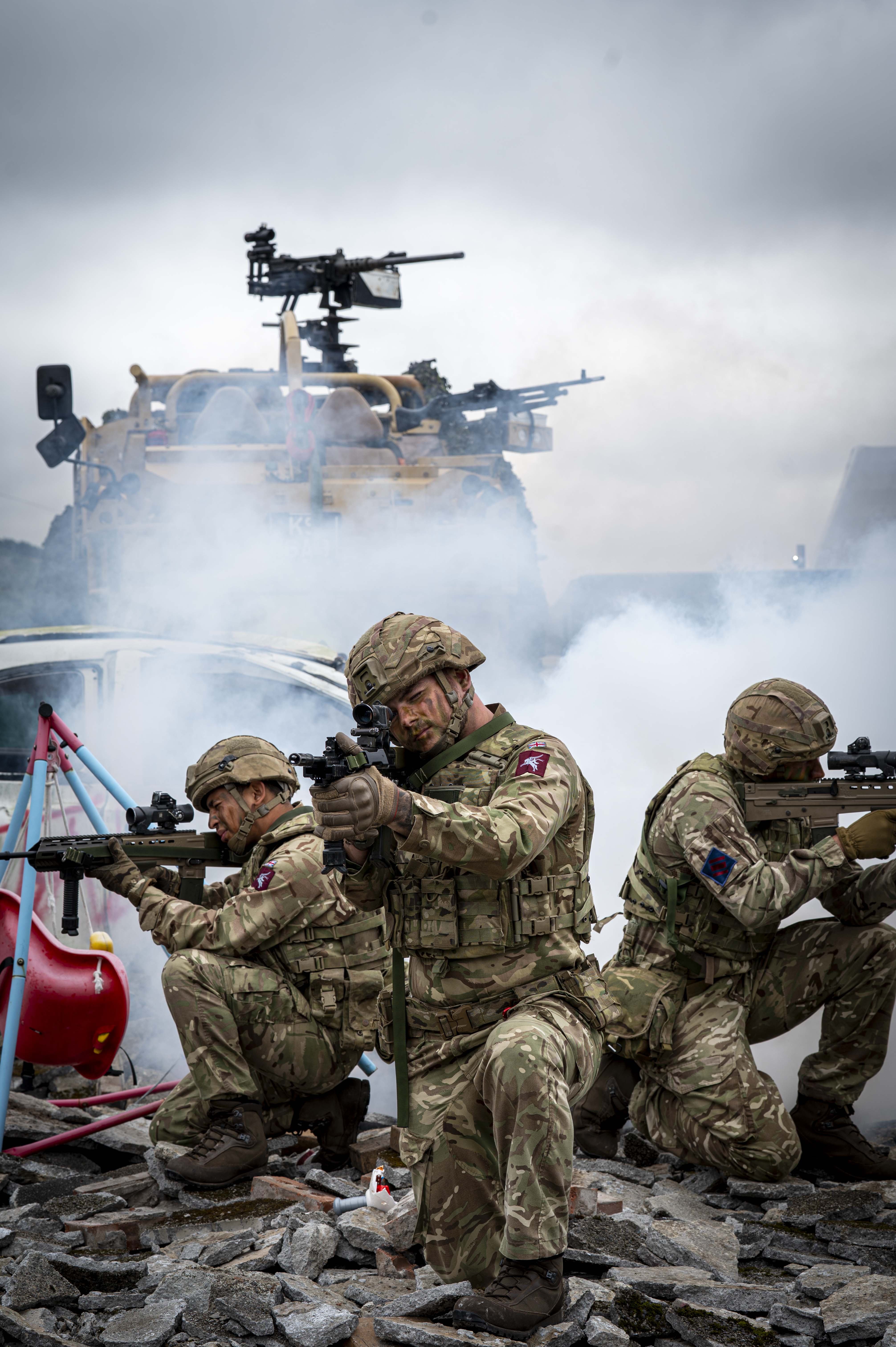 Soldiers shown demonstrate an attack scenario outside with debris including a child's swing, a car and white goods and a jackal with Soldiers in coming through the back.