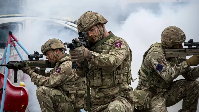 Soldiers shown demonstrate an attack scenario outside with debris including a child's swing, a car and white goods and a jackal with Soldiers in coming through the back.