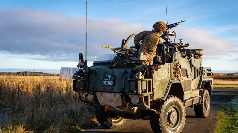 A soldier in uniform is pictured on the back of a green Army vehicle.