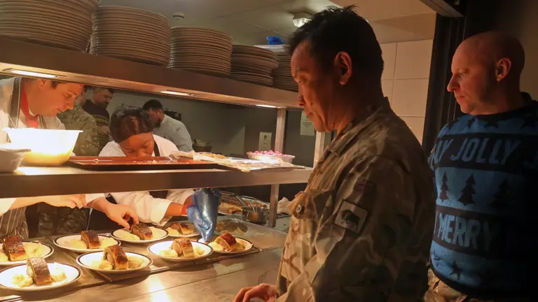 Soldiers prepare to receive food from a kitchen.