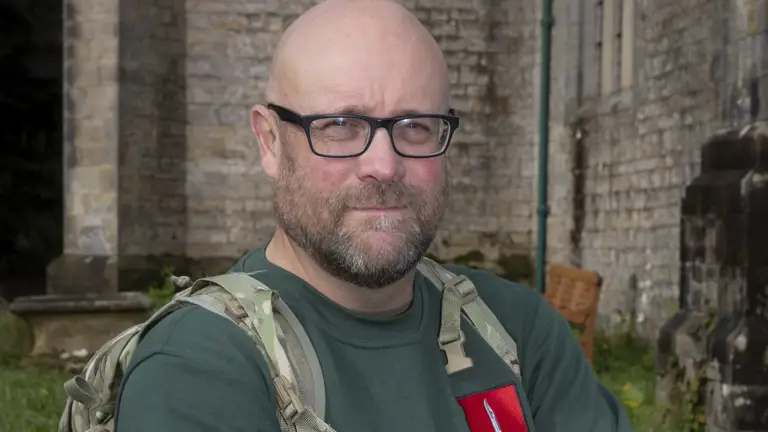 Portrait of a soldier seen in a plain top and a camouflage back pack posing for a photo