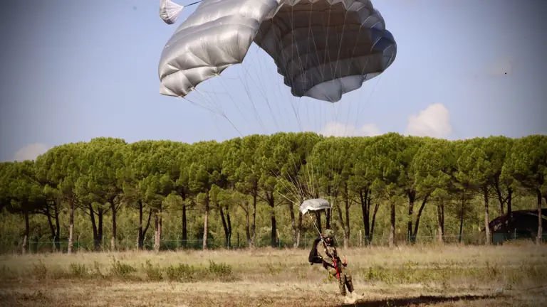 A soldier lands from a parachute jump.