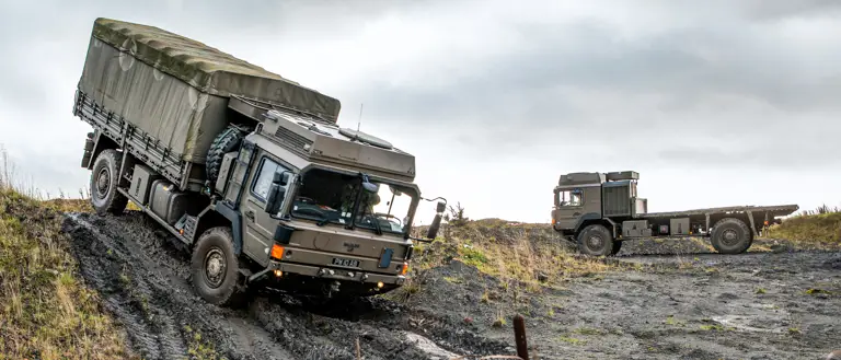 A military truck drives down a muddy track.