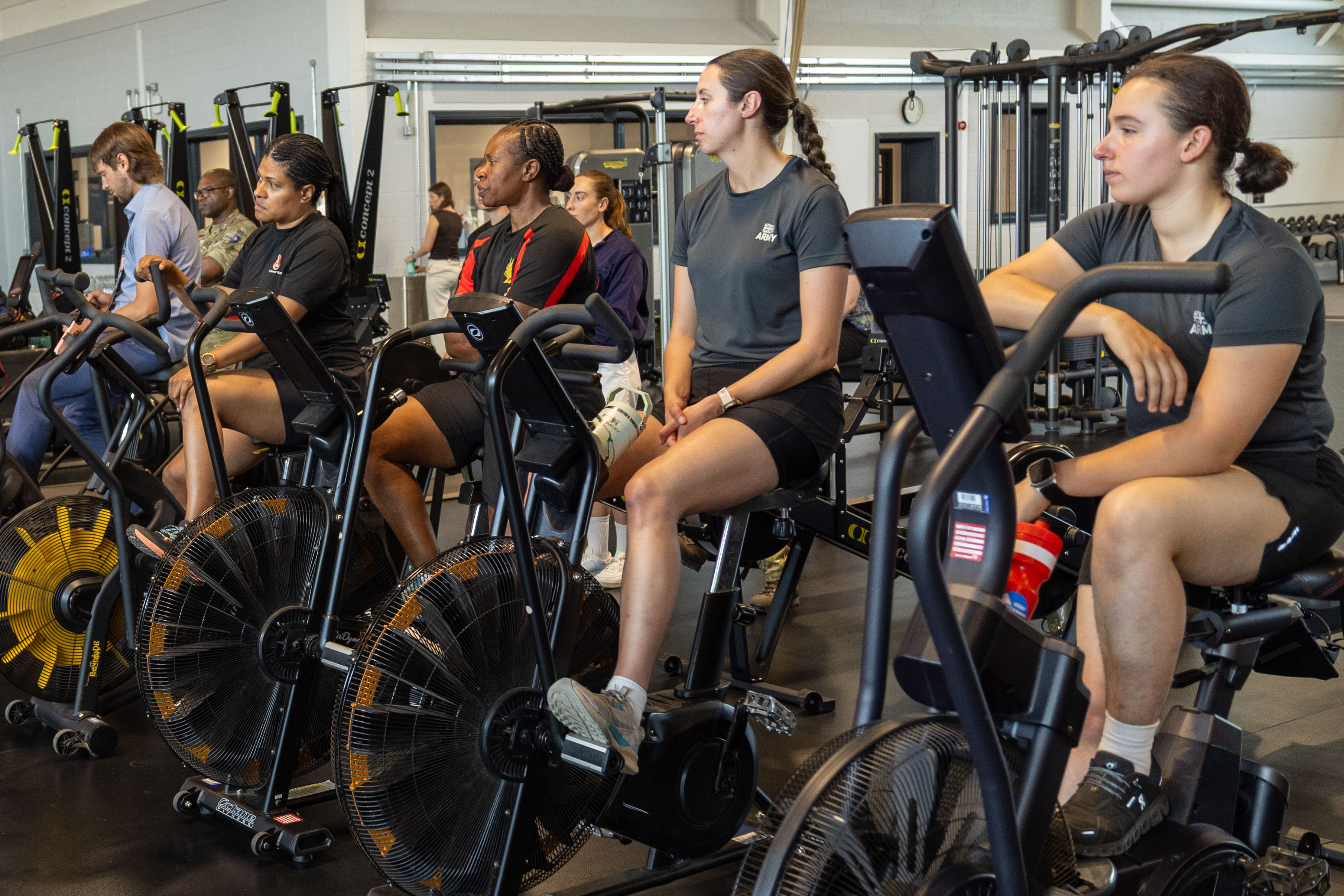 A group of individuals are sat on stationary bikes in a gym.