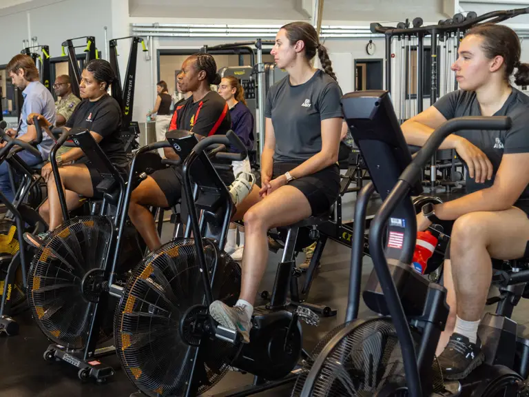 A group of individuals are sat on stationary bikes in a gym.
