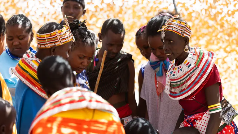 A group of Kenyan locals are pictured, some are wearing bright and multi-coloured clothing.