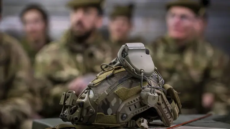 A close up of a green military helmet with in built ear defence.