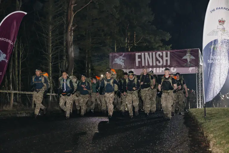 Soldiers shown crossing the start line in the Lanyard Trophy Competition in the wet weather and dark skies early in the morning.