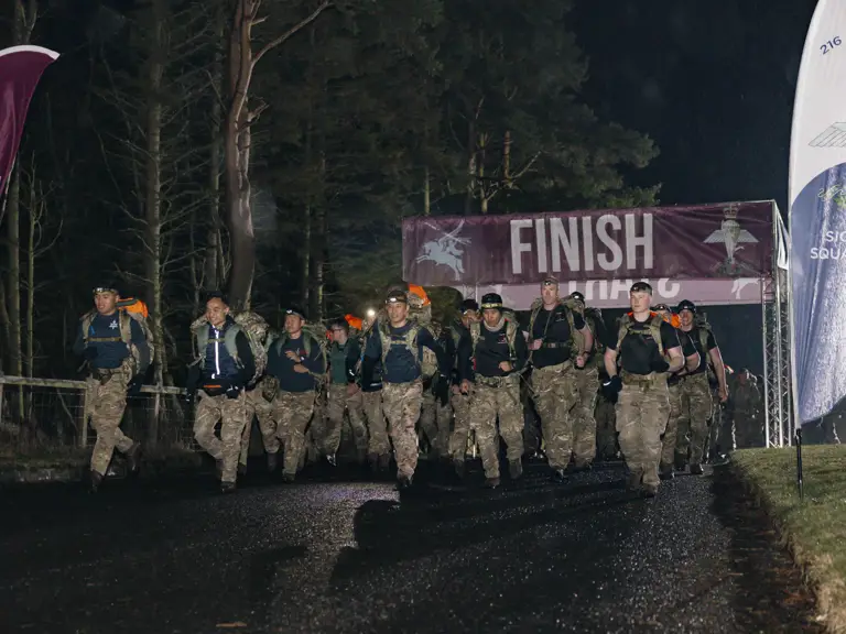 Soldiers shown crossing the start line in the Lanyard Trophy Competition in the wet weather and dark skies early in the morning.