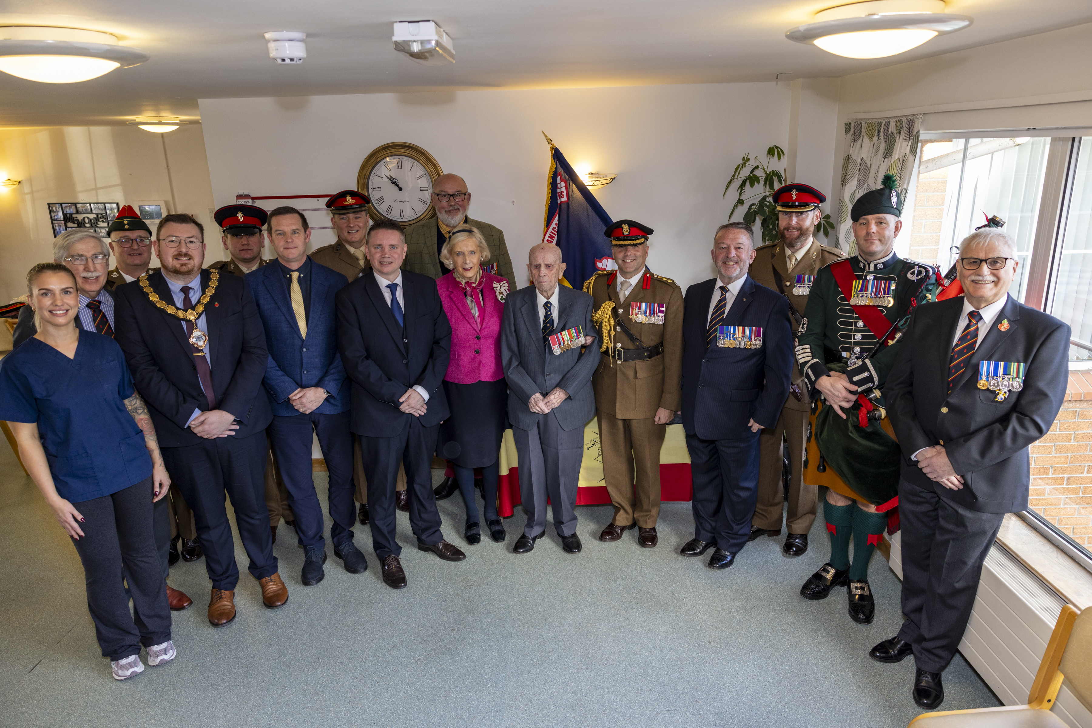 Sixteen people stood posing for a photo, all who attended birthday celebrations.