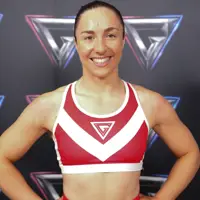 Athletic woman in a red and white sports bra posing confidently against a backdrop with repeating geometric logos.