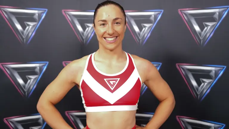 Athletic woman in a red and white sports bra posing confidently against a backdrop with repeating geometric logos.