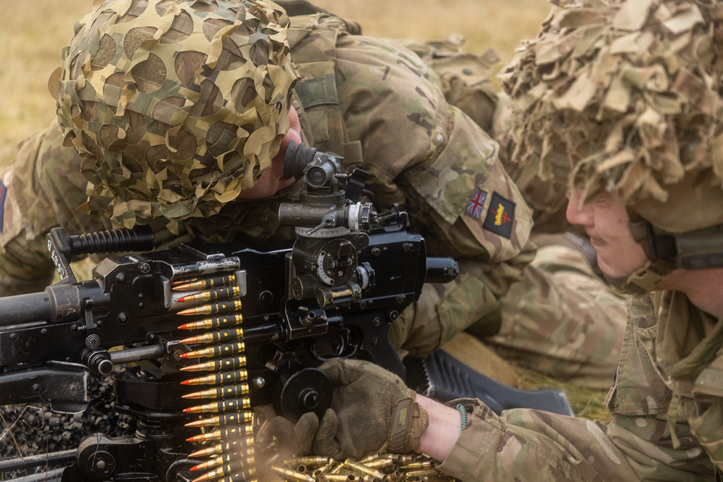 Two soldiers lay next to a machine gun preparing to fire.