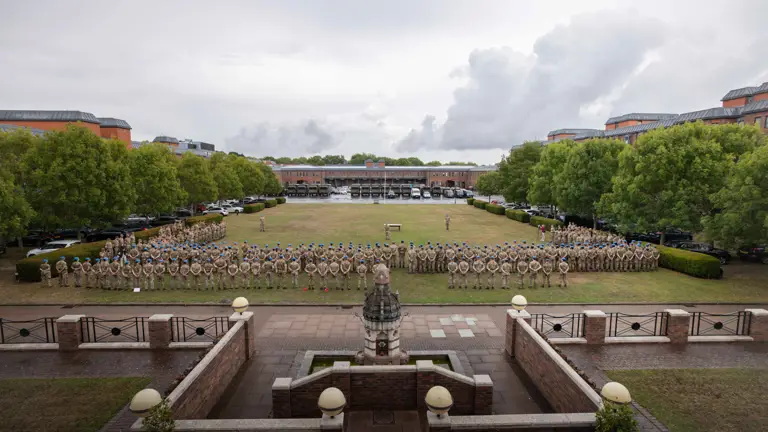 Soldiers in camouflage uniforms stand on a parade.